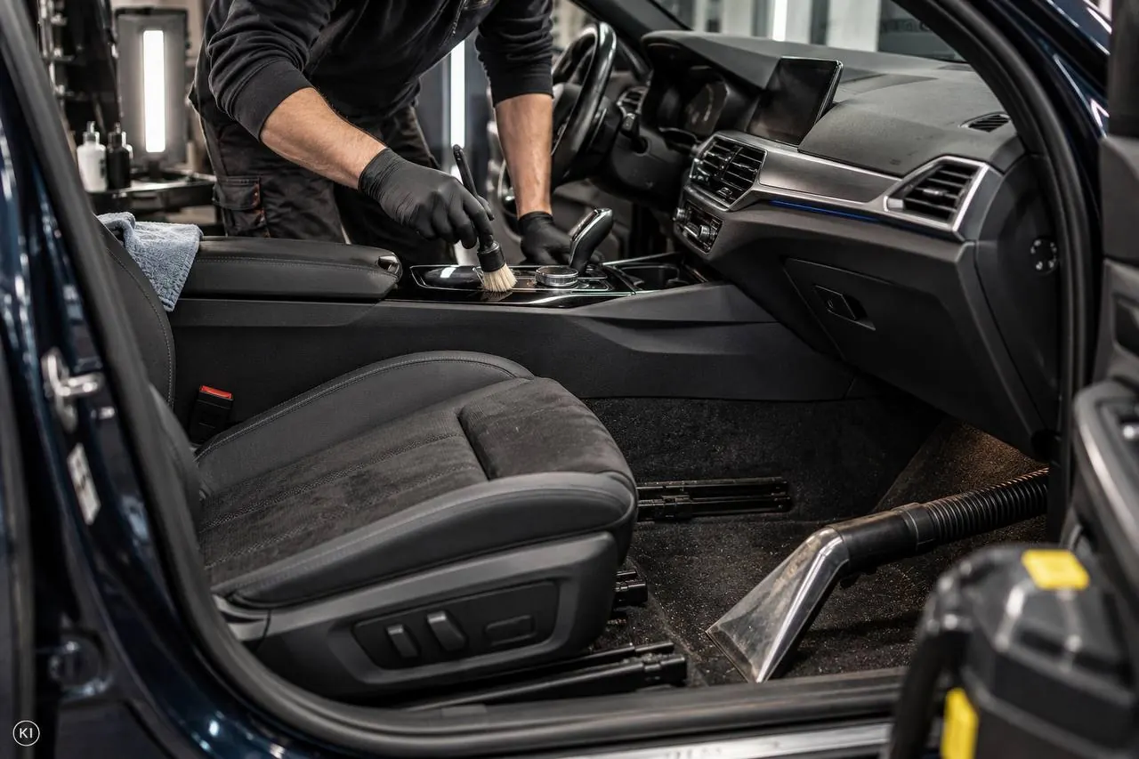 Mitarbeiter arbeitet an Sitz und Innenraum eines geöffneten Fahrzeugs.